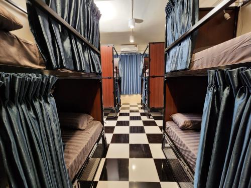 a room with bunk beds on a checkered floor at Noir Cafe And Hostel - Chinatown Bangkok in Pom Prap