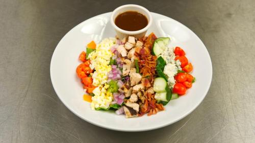 a white plate with a salad and a cup of sauce at Holiday Inn - Mississauga Toronto West by IHG in Mississauga