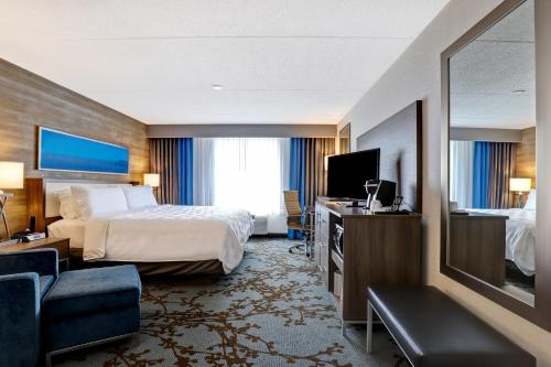 Holiday Inn - Mississauga Toronto West, an IHG Hotel في ميسيساوغا: غرفه فندقيه سرير وتلفزيون