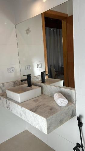 Cuenta con una encimera con 2 lavabos y un espejo. en Chalé Recanto das Estrelas en Monte Verde