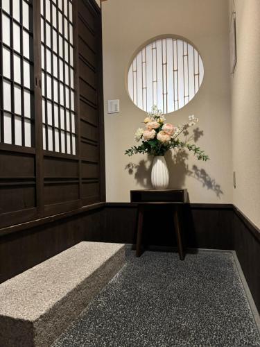 um vaso de flores sentado numa mesa numa sala em 京都駅そばの一棟貸し京町家 suiten shichijo 萃点七条 em Quioto
