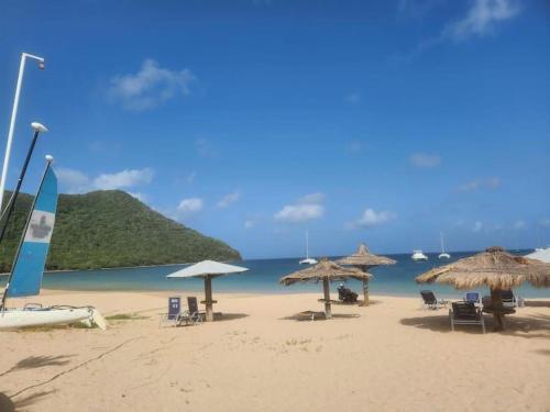 una playa con sombrillas y sillas y el océano en Premium Travel Escapes - Studio Apartment en Rodney Bay Village