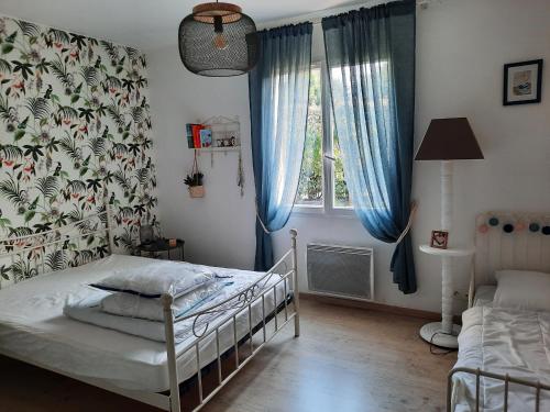 Schlafzimmer mit einem Bett und einem Fenster mit blauen Vorhängen in der Unterkunft Maison Seignosse, 5 pièces, 9 personnes - FR-1-239-1033 in Seignosse