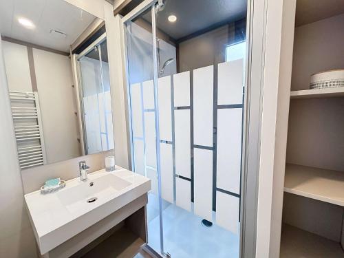 une salle de bain avec un lavabo et une douche en verre dans l'établissement Chalet cozy à Jullouville - 4 pers, piscine chauffée, proche plage et commerces - FR-1-361-538, à Jullouville