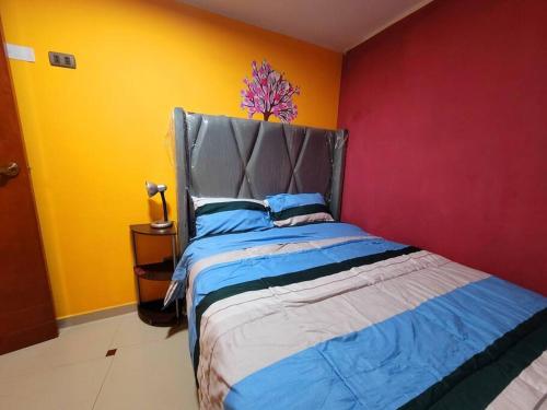 a bedroom with a bed with a red and yellow wall at Apartamento Panorámico in Cajamarca
