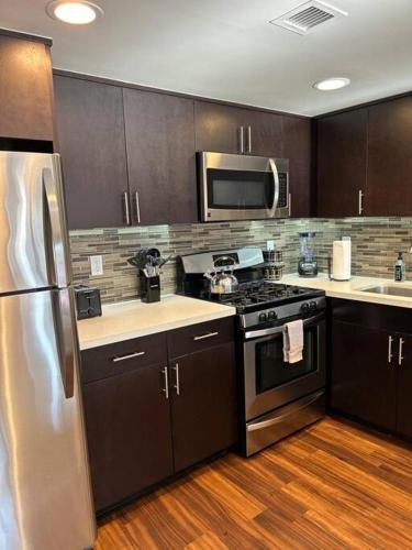 a kitchen with stainless steel appliances and wooden floors at Downtown LA - Mamba Suite - Free Indoor Parking! in Los Angeles