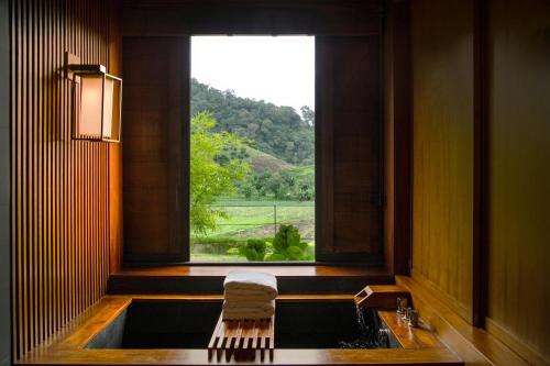 a bathroom with a sink and a window with a view at Onsen at Moncham in Mae Rim