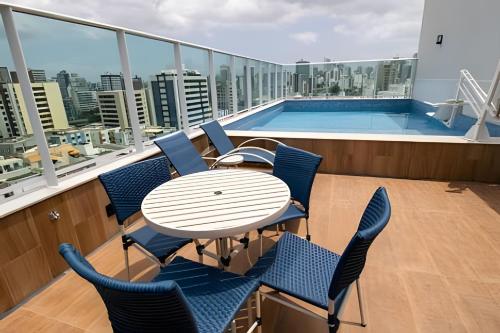 een balkon met een tafel en stoelen en een zwembad bij Novo Apt. 2 Quartos Vista Mar Salvador in Salvador