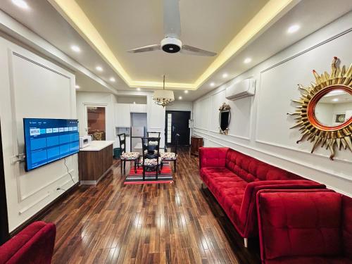 a living room with a red couch and a tv at Executive 2BHK Apt in Elysium tower Isb in Islamabad