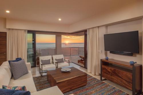 uma sala de estar com uma televisão de ecrã plano e um sofá em Beachfront 2 Bdrm Condo in Exclusive Diamante Golf em Cabo San Lucas