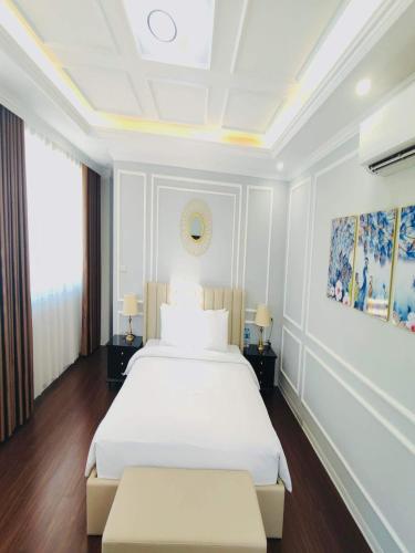 - une chambre avec un grand lit blanc et 2 tables dans l'établissement Villa FLC 7 Ngủ Hạ Long - Đẳng cấp - Phòng Karaoke riêng, à Hạ Long