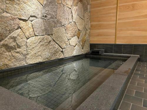 - Baño con piscina y pared de piedra en Matsumoto Ryokan, en Kioto