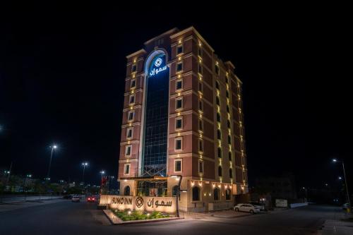 un grand bâtiment avec une tour d'horloge la nuit dans l'établissement فندق سمو ان - Sumo inn Hotel, à Najran