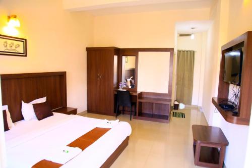 a bedroom with a bed and a desk and a television at Highrange Plaza in Thekkady