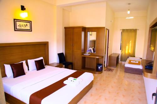 a hotel room with a large bed and a desk at Highrange Plaza in Thekkady