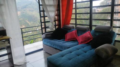 a blue couch in a room with a large window at Apartamento hermosa vista in Líbano