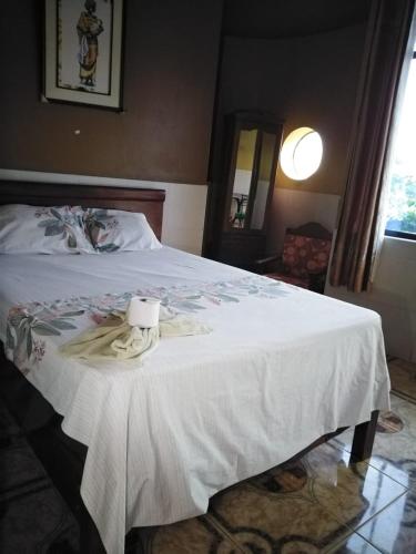 a bed with a white blanket and a candle on it at Hospedaje Kennedy in Pucallpa