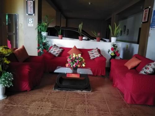uma sala de estar com sofás vermelhos e uma mesa com flores em Hospedaje Kennedy em Pucallpa