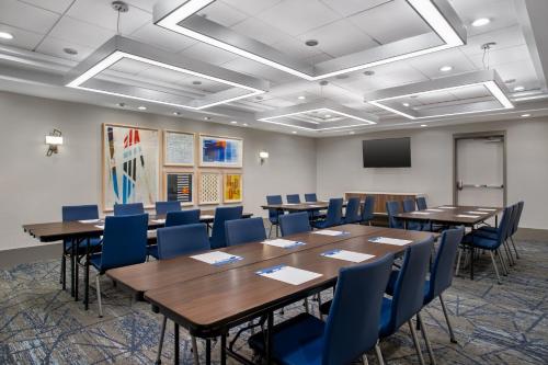 a conference room with tables and chairs and a screen at Holiday Inn Express Hotel & Suites Terre Haute by IHG in Terre Haute