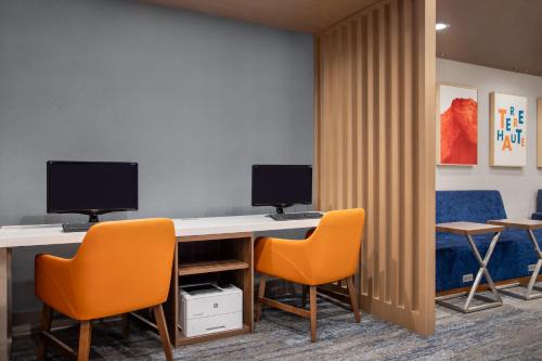 an office with two monitors on a desk with chairs at Holiday Inn Express Hotel & Suites Terre Haute by IHG in Terre Haute