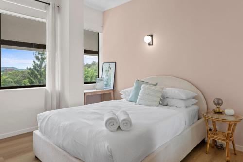 a white bedroom with a bed with two white towels on it at Urban Chic Brisbane Retreat in Brisbane