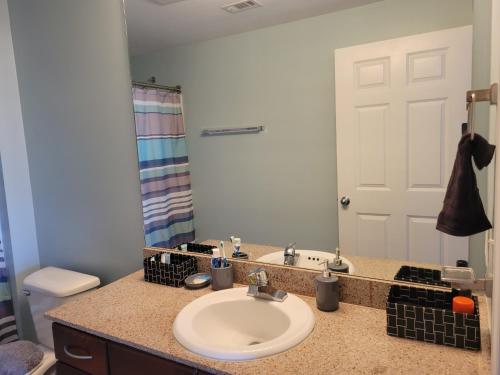 a bathroom with a sink and a toilet and a mirror at Spectacular 5th Floor Gulf View Condo in Panama City Beach, just steps away from the beach in Panama City Beach