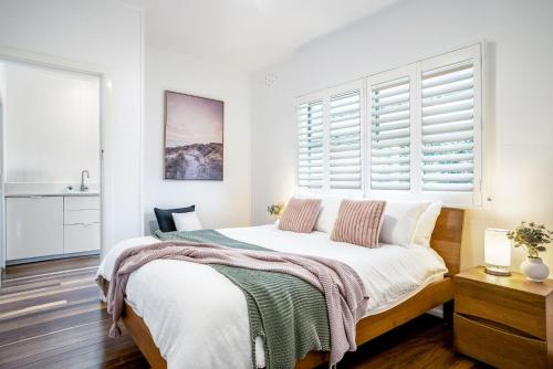 a bedroom with a bed with white walls and a window at 1-29 Beech Street in Evans Head