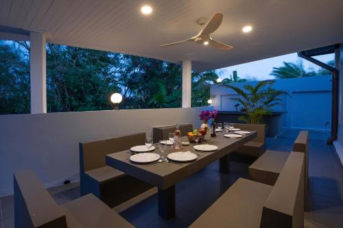 a dining room with a table and chairs and a ceiling fan at 3BR Villa Marine with Private Pool, Waterfalls in NaiHarn Beach in Rawai Beach