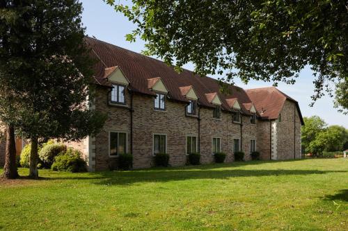 a large brick building with a gambrel roof at voco Oxford Thames by IHG in Oxford