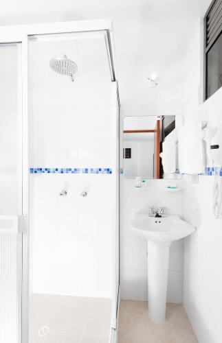 a white bathroom with a shower and a sink at Hotel Puerto Bahia in San Gil