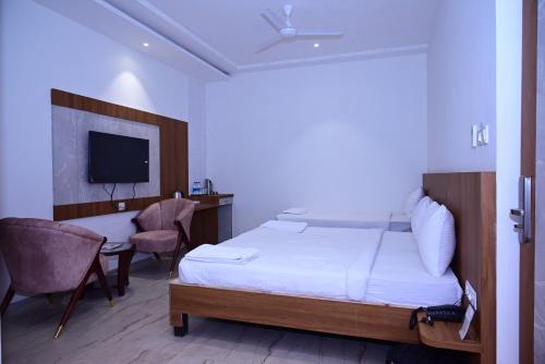 Schlafzimmer mit einem Bett, einem Schreibtisch und einem TV in der Unterkunft Hotel City Grand Varanasi in Varanasi