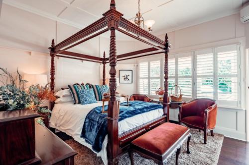 1 dormitorio con cama con dosel, mesa y sillas en Rosemont House Luxury BnB, en Noojee