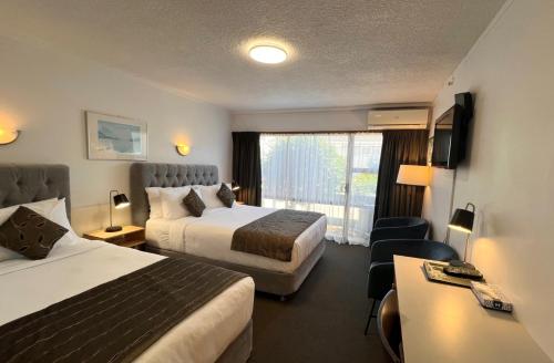 a hotel room with two beds and a window at Alpers Lodge & Conference Centre in Auckland