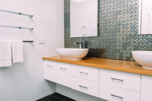 ein Badezimmer mit 2 Waschbecken und einem Spiegel in der Unterkunft LUX Glenelg - Pool 4BD 3BA Sleeps 13 in Glenelg