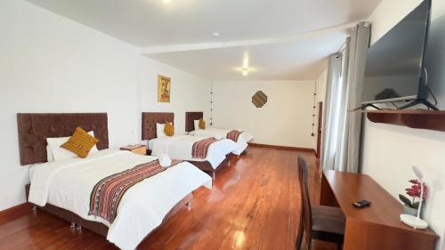 two beds in a room with a television and a desk at Casona Liberty Inn in Cusco