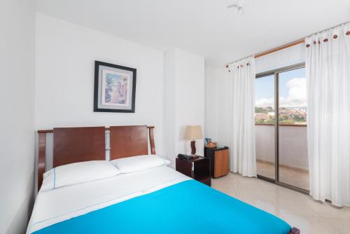 a bedroom with a bed and a large window at Hotel Puerto Bahia in San Gil