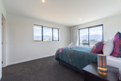 a bedroom with a bed and two windows at Oraka Scenery - Te Anau Holiday Home in Te Anau