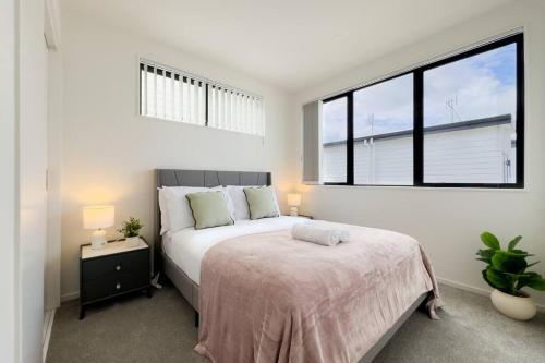 a bedroom with a bed and a large window at Brand New 3Bedroom Retreat in South Auckland in Takanini