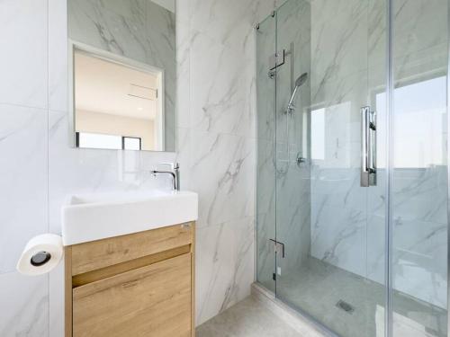 a bathroom with a shower and a sink and a mirror at Brand New 3Bedroom Retreat in South Auckland in Takanini