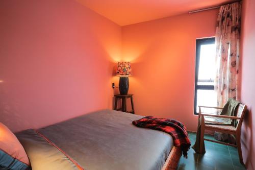 a bedroom with orange walls and a bed and a window at Âm Ấm Đà Lạt Boutique Hotel & Cozy Bistro in Khu Chi Lăng