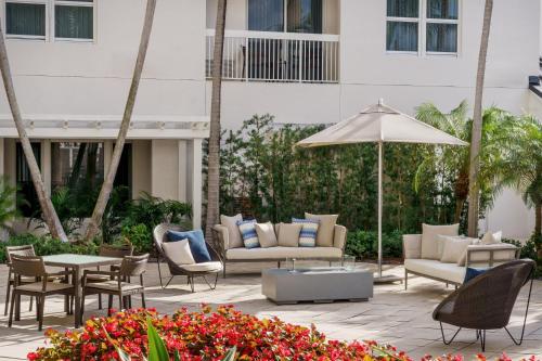 a patio with chairs and tables and an umbrella at Courtyard by Marriott Miami Aventura Mall in Aventura