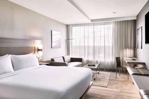 ブリッジウォーターにあるAC Hotel by Marriott Bridgewaterの白いベッドとソファが備わるホテルルームです。