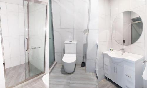 a white bathroom with a toilet and a sink at AWA Hotel in Rotorua