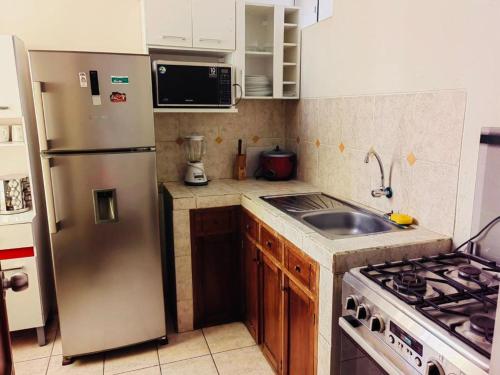 eine Küche mit einem Kühlschrank aus Edelstahl und einer Spüle in der Unterkunft Exclusivo Apartamento en el Centro de Trujillo in Trujillo