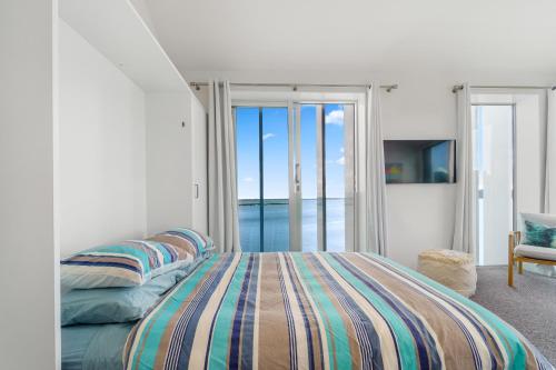 a bedroom with a bed with a view of the ocean at Harbour View - Westmere Holiday Apartment in Auckland