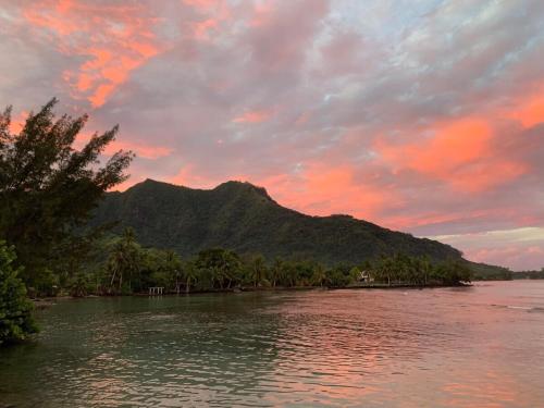 a sunset over a river with a mountain in the background at Fare Orahana Moorea in Afareaitu