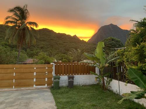 a fence with a palm tree and mountains in the background at Fare Orahana Moorea in Afareaitu