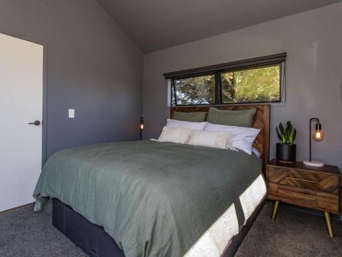 a bedroom with a large bed and a window at Sno Ruapehu - Horopito Holiday Home in Raetihi