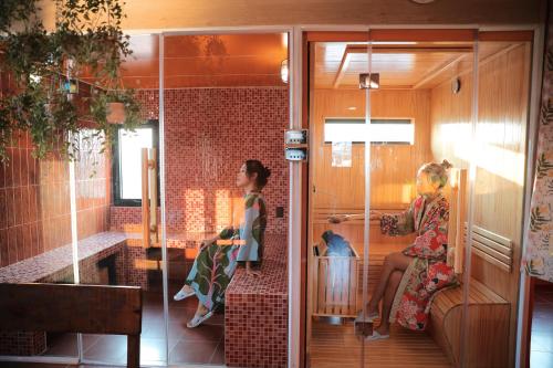 two women sitting in a bathroom with a sink at Âm Ấm Đà Lạt Boutique Hotel & Cozy Bistro in Khu Chi Lăng