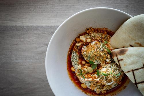 a bowl of food with eggs and beans on a table at Kamana Lakehouse in Queenstown